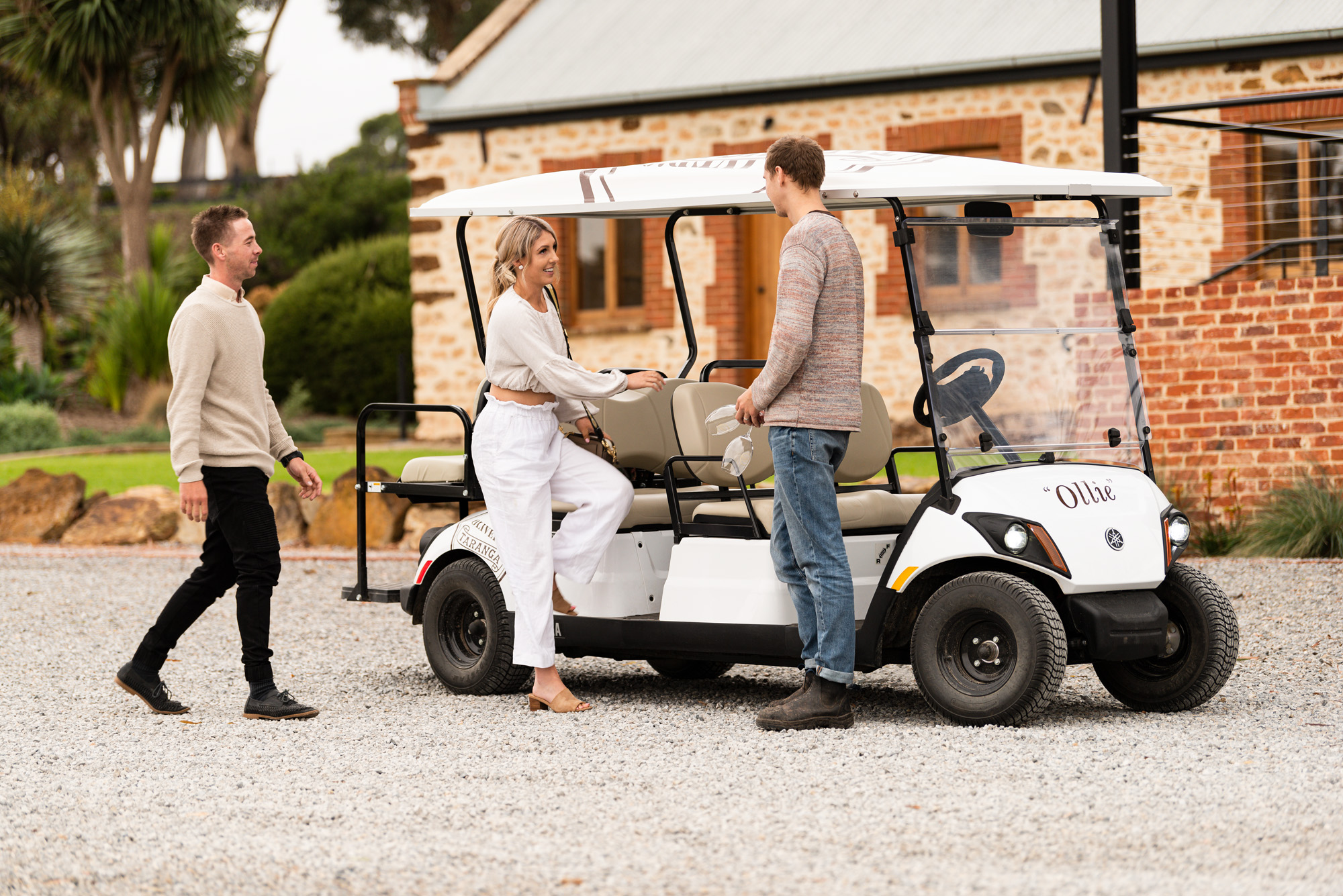 A woman and 2 men and a golf cart 